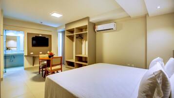 Habitación de hotel con cama, escritorio, silla, armario y equipo de aire acondicionado.