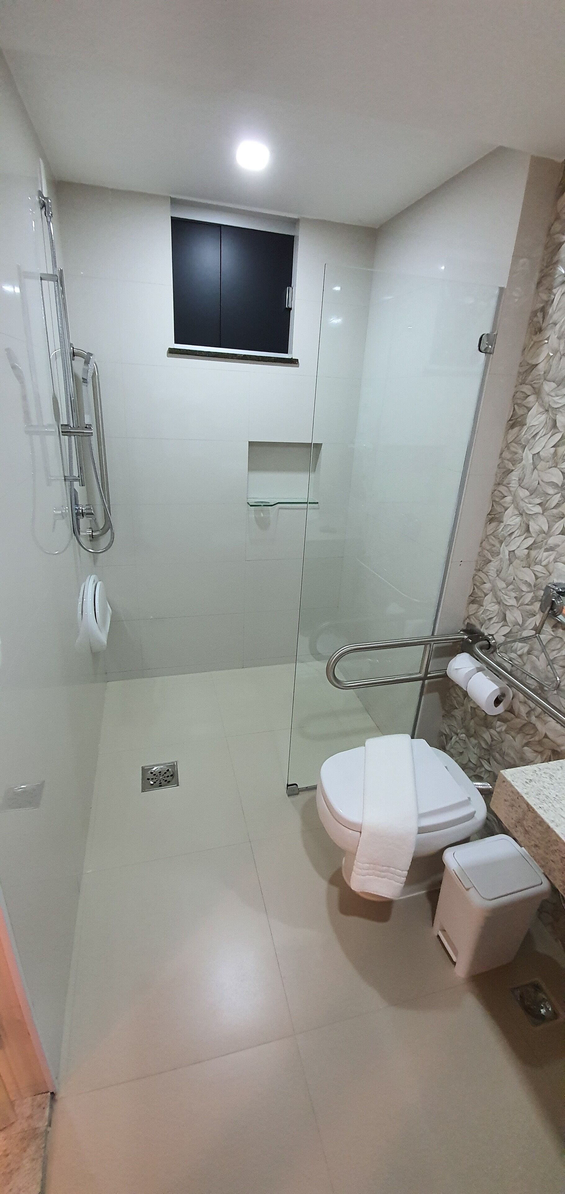 A modern bathroom with a glass-enclosed shower, a toilet, and a sink.