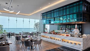 Ein modernes Restaurant mit Meerblick, ausgestattet mit einer Marmorplatte und einem Koch, der zubereitet.