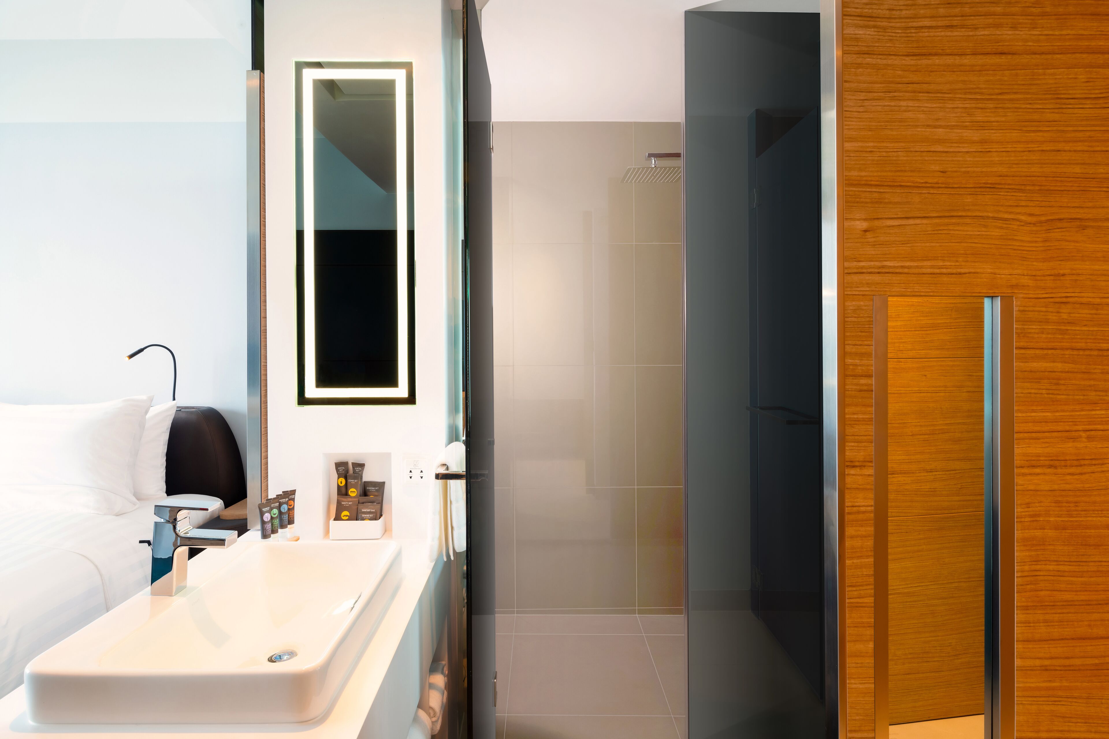 A modern bathroom with a white sink, a mirror, and a shower area.