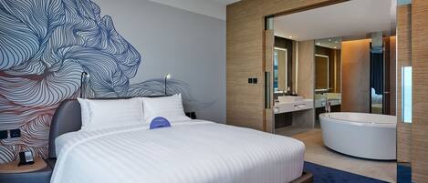 Una habitación de hotel moderna con una cama grande, un baño con bañera y un diseño de arte mural original.