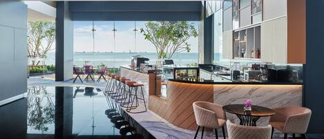 Un área de bar moderna con una barra larga, taburetes y vistas al mar.