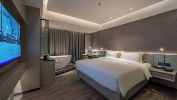 A modern hotel room with a large bed, a TV, a bathroom, and a desk.