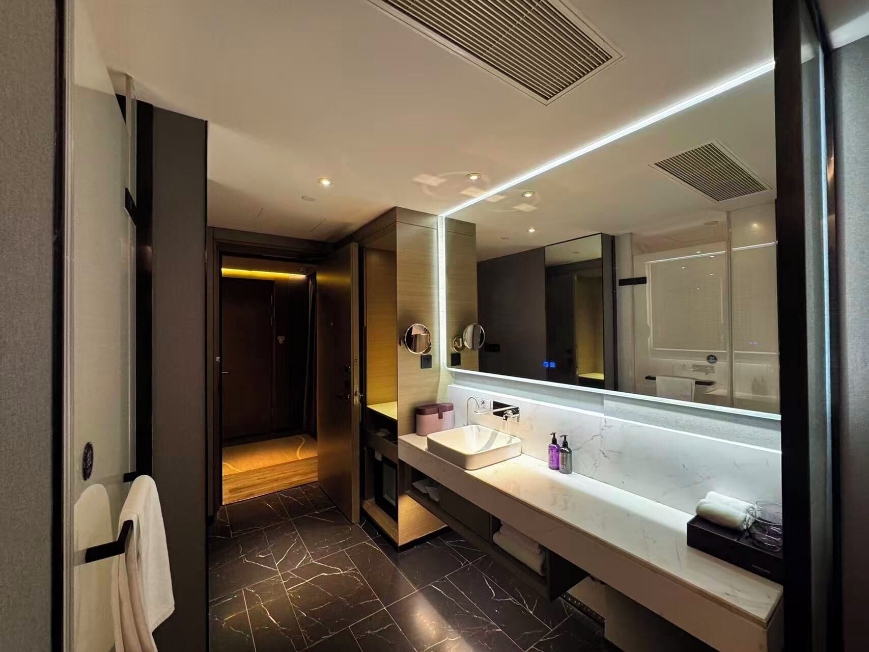 Une salle de bain moderne avec un grand miroir, un meuble-lavabo et un espace douche.
