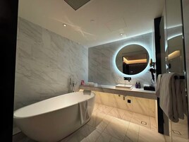 A modern bathroom with a freestanding bathtub, a round mirror, and a vanity with a sink.