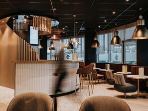 A modern interior with a curved reception desk, seating area, and large windows. - Novotel Angers Centre Gare (Angers)
