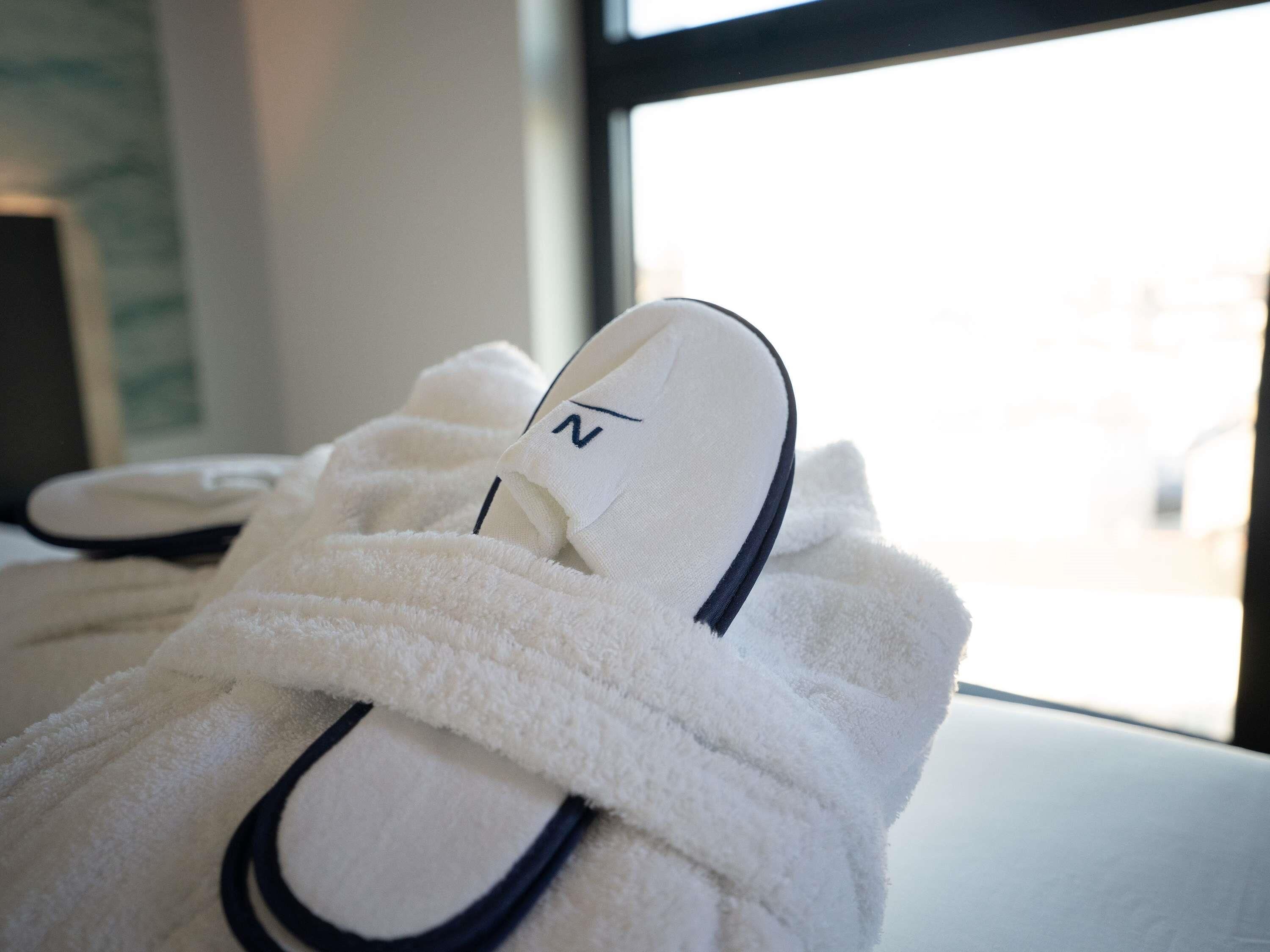 A pair of white slippers with a navy blue accent on a white surface.