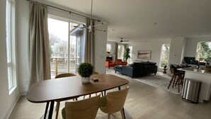 A modern living room with a dining area, a kitchen, and a balcony. - 5 Queen Bed 4 Full Bath Luxury Home, 1.4 miles to Bank of America Stadium (Charlotte)