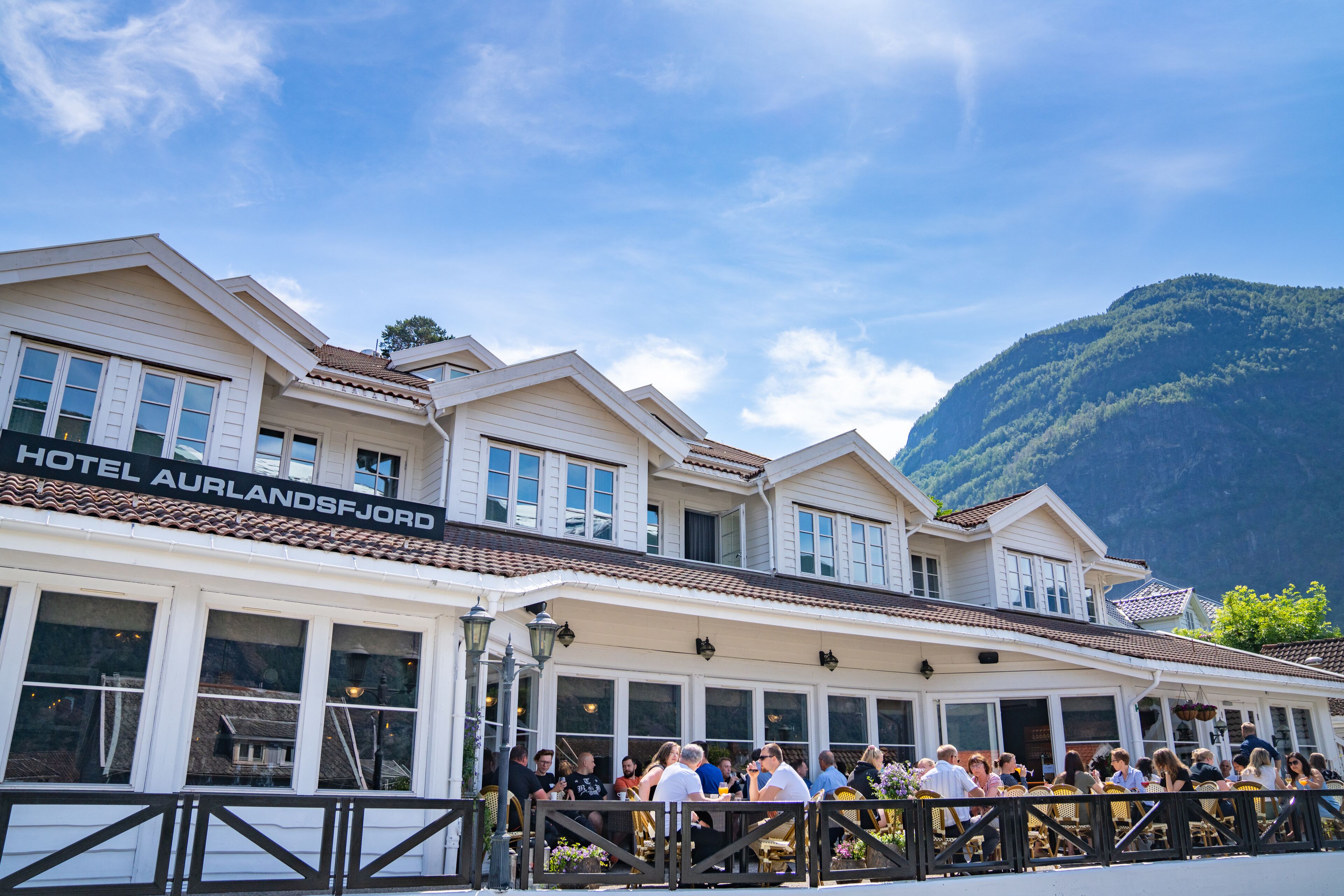 A hotel with a sign reading "HOTEL AURLANDSJORD" and a crowd of people outside.