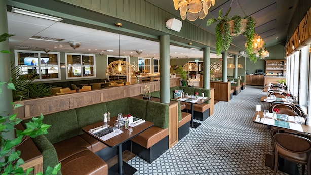 Un restaurante con asientos tipo cabina, plantas colgantes e iluminación colgante.