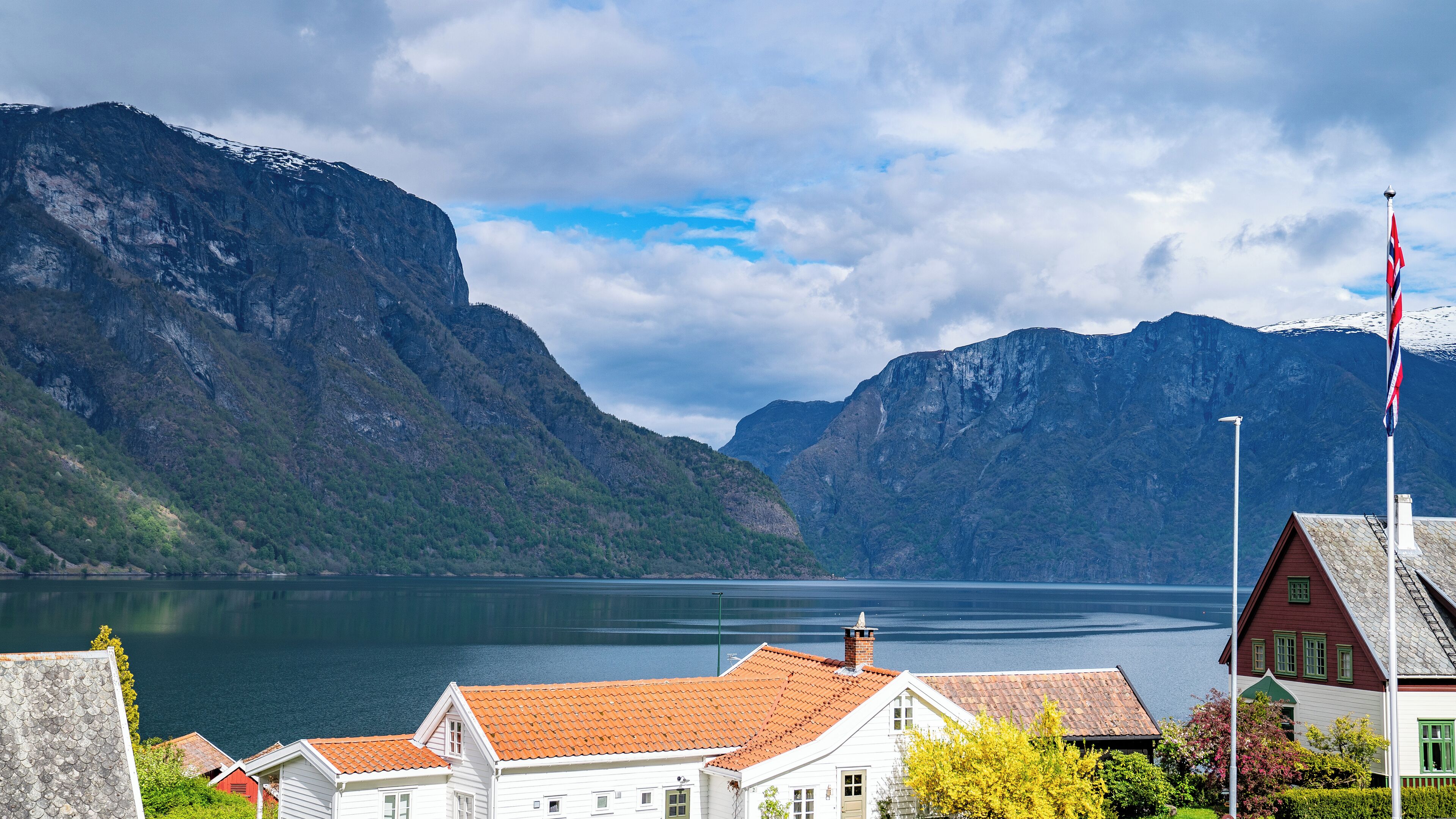 A coastal village with traditional houses, a fjord, and mountains in the background.
