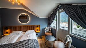 Habitación de hotel con cama, una mesa redonda, una silla, vistas al exterior y una lámpara en el techo.
