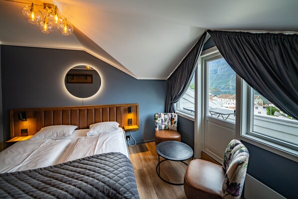 Habitación de hotel con cama, una mesa redonda, una silla, vistas al exterior y una lámpara en el techo.