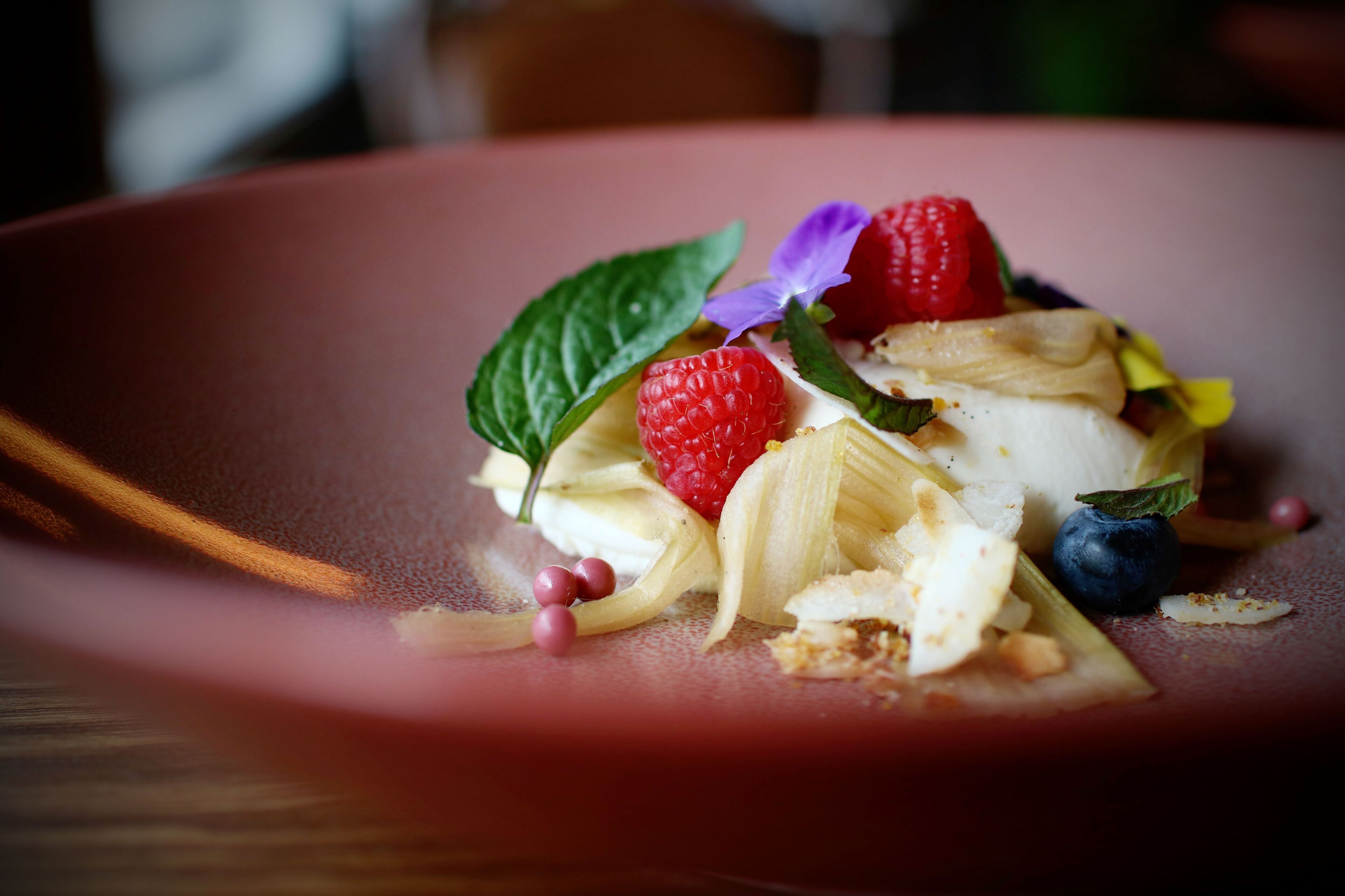 A dessert with fruits and leaves on a plate.