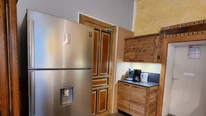 Eine kleine Küche mit Edelstahl-Kühlschrank, Holzschränken und einer Kaffeemaschine auf der Arbeitsfläche.