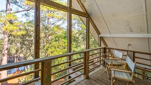 A wooden deck with a railing, overlooking a forested area.