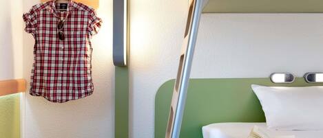 A bunk bed with a green headboard, a hanging shirt, a handbag, and a book on the bed.