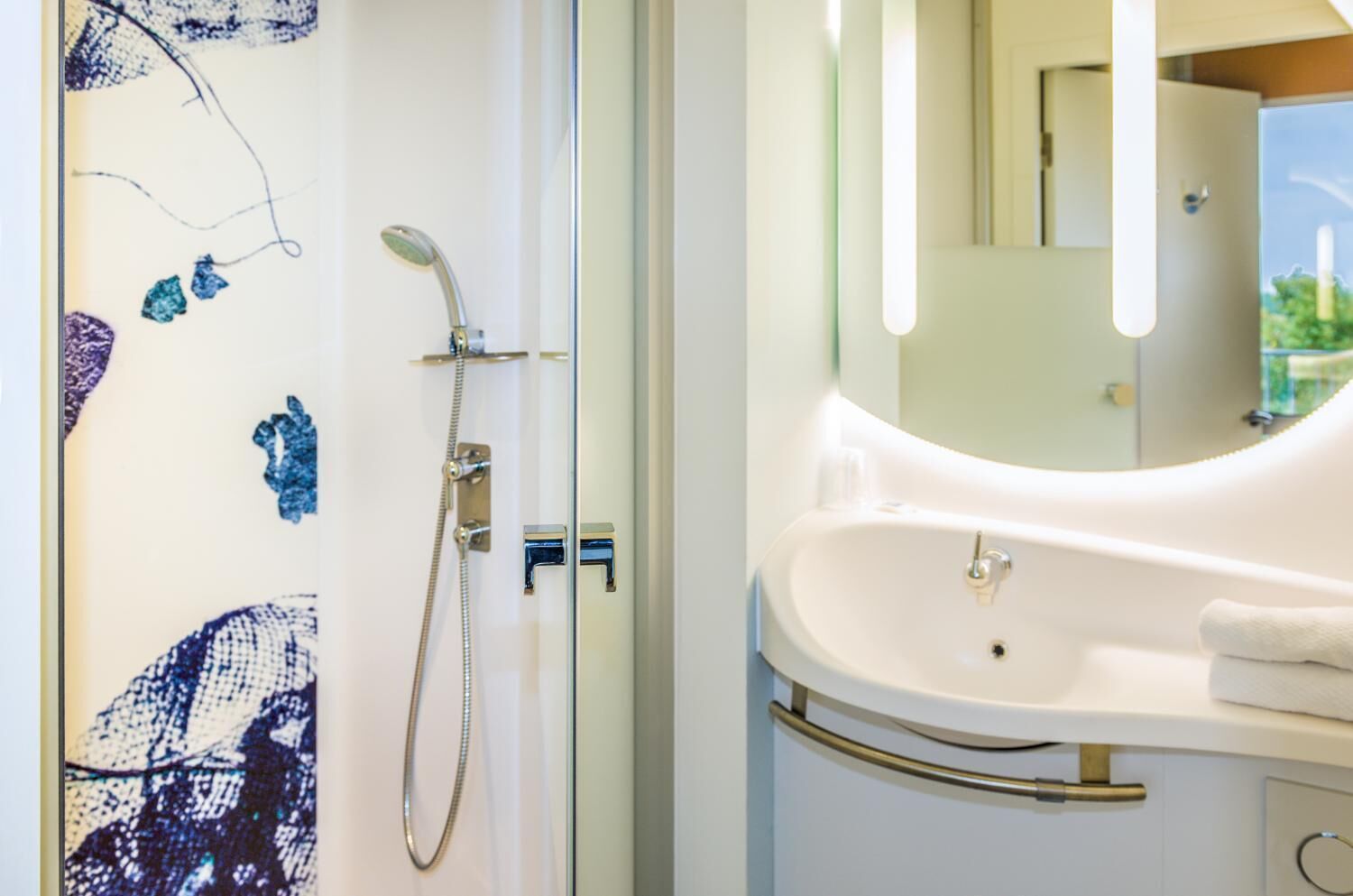 Ein Badezimmer mit Dusche, Waschbecken und Spiegel.