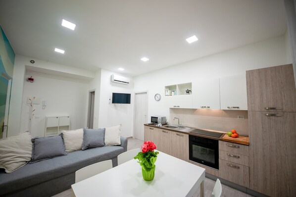 A modern apartment with a living area, kitchenette, and a dining table with a vase of flowers. - Ines - 2-4 people (Albenga)