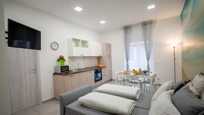 A modern apartment with a kitchenette, a dining area, and a living room with a sofa and pillows.