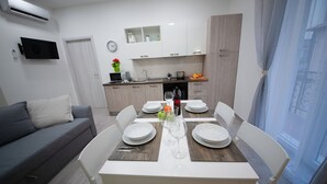 A modern kitchen with white cabinets, a built-in oven, and a dining area with a white table set for four.