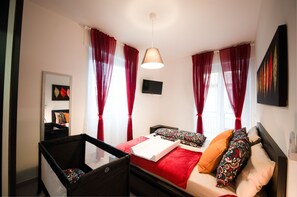A bedroom with a bed, a chair, a TV, and red curtains. - Ines - 2-4 people (Albenga)