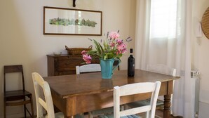 Ein Esstisch mit Blumen in einer Vase, einer Weinflasche und einem gerahmten Bild an der Wand.