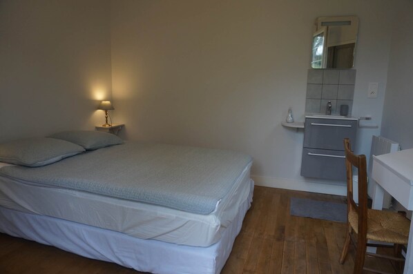 A bedroom with a bed, a bedside lamp, a small table, a chair, a mirror, and a dresser. - Le Clos du 10 - 4-star listed house (Treignac)