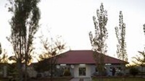 Un bâtiment avec un toit rouge, entouré d’arbres et bordé d’un chemin pavé.