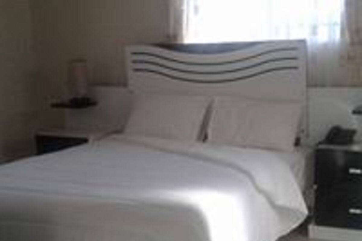 Quarto com cama, mesa de cabeceira e cômoda.