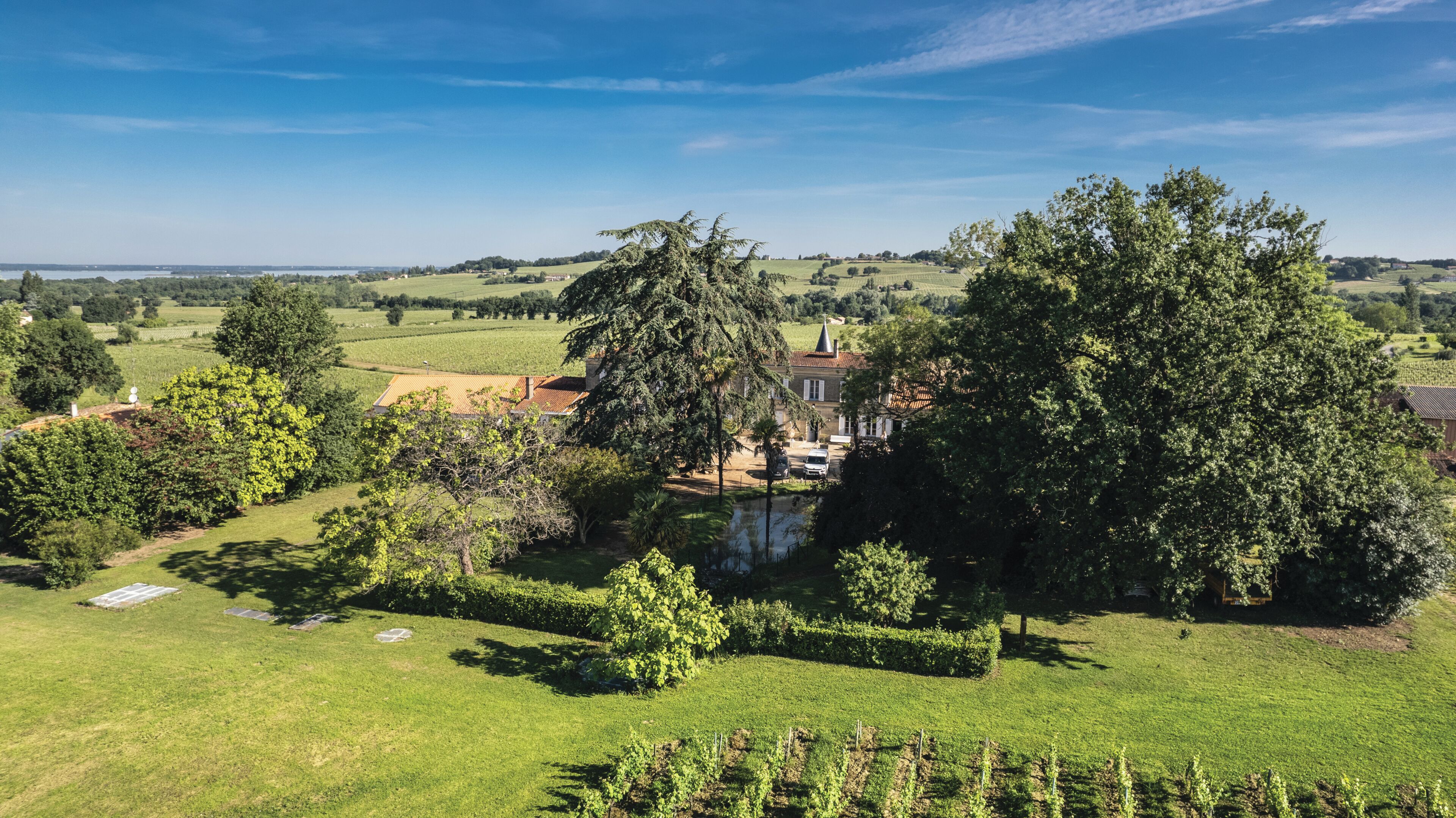 A rural estate with a large house surrounded by lush greenery and fields.