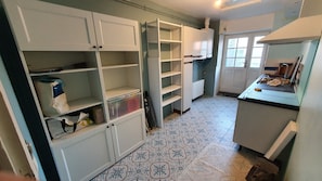 A kitchen with white cabinets, patterned floor tiles, and a countertop with kitchen utensils. - Typical house in Cancale (Cancale)