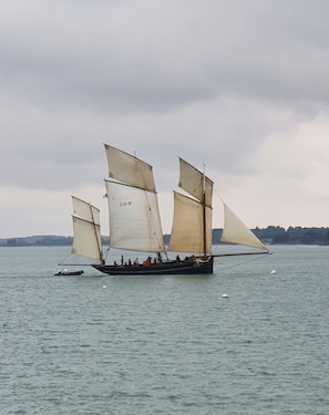 A sailboat with multiple sails on a body of water. - Typical house in Cancale (Cancale)