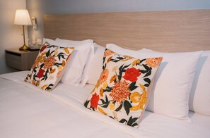 A neatly made bed with white linens and two decorative pillows with a floral pattern. - Casa Franco Hotel (Cartagena)