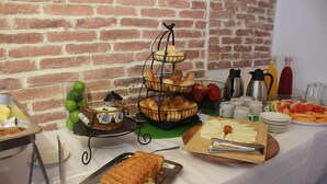 A buffet table with various food items, including bread, fruits, and beverages. - Casa Franco Hotel (Cartagena)