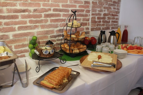 A buffet table with various food items, including bread, fruits, and beverages. - Casa Franco Hotel (Cartagena)