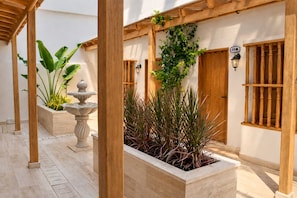 A courtyard with a wooden pergola, a stone fountain, and potted plants. - Casa Franco Hotel (Cartagena)