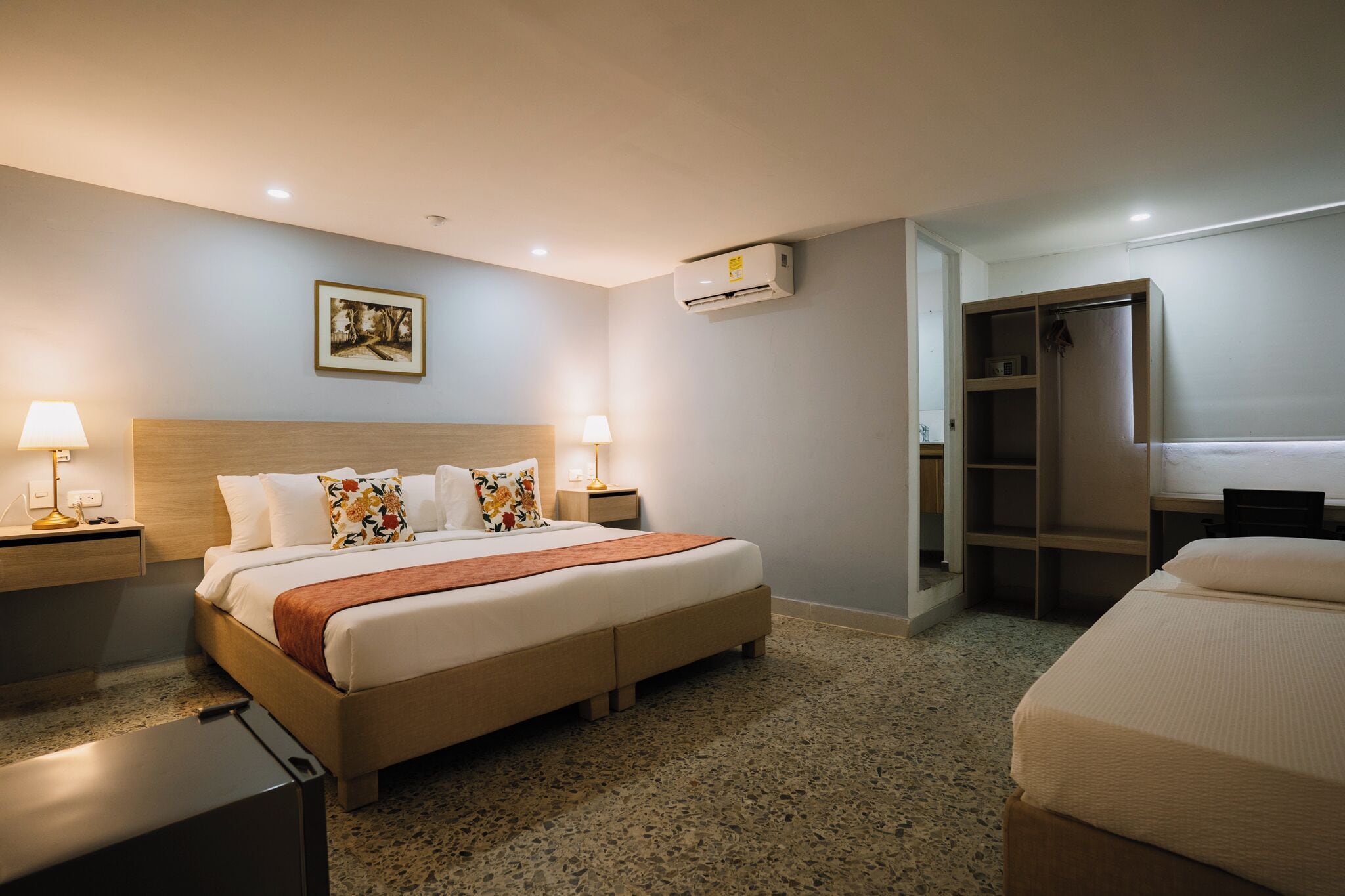 Une chambre d’hôtel comprenant un lit, des tables de chevet, une armoire et un appareil de climatisation.