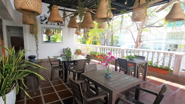 An outdoor patio with wicker hanging lamps, a tiled floor, and several tables and chairs. - Casa Franco Hotel (Cartagena)