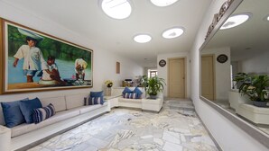 A spacious lobby with a large painting, a white sofa with blue cushions, a marble floor, and a potted plant. - Casa Franco Hotel (Cartagena)