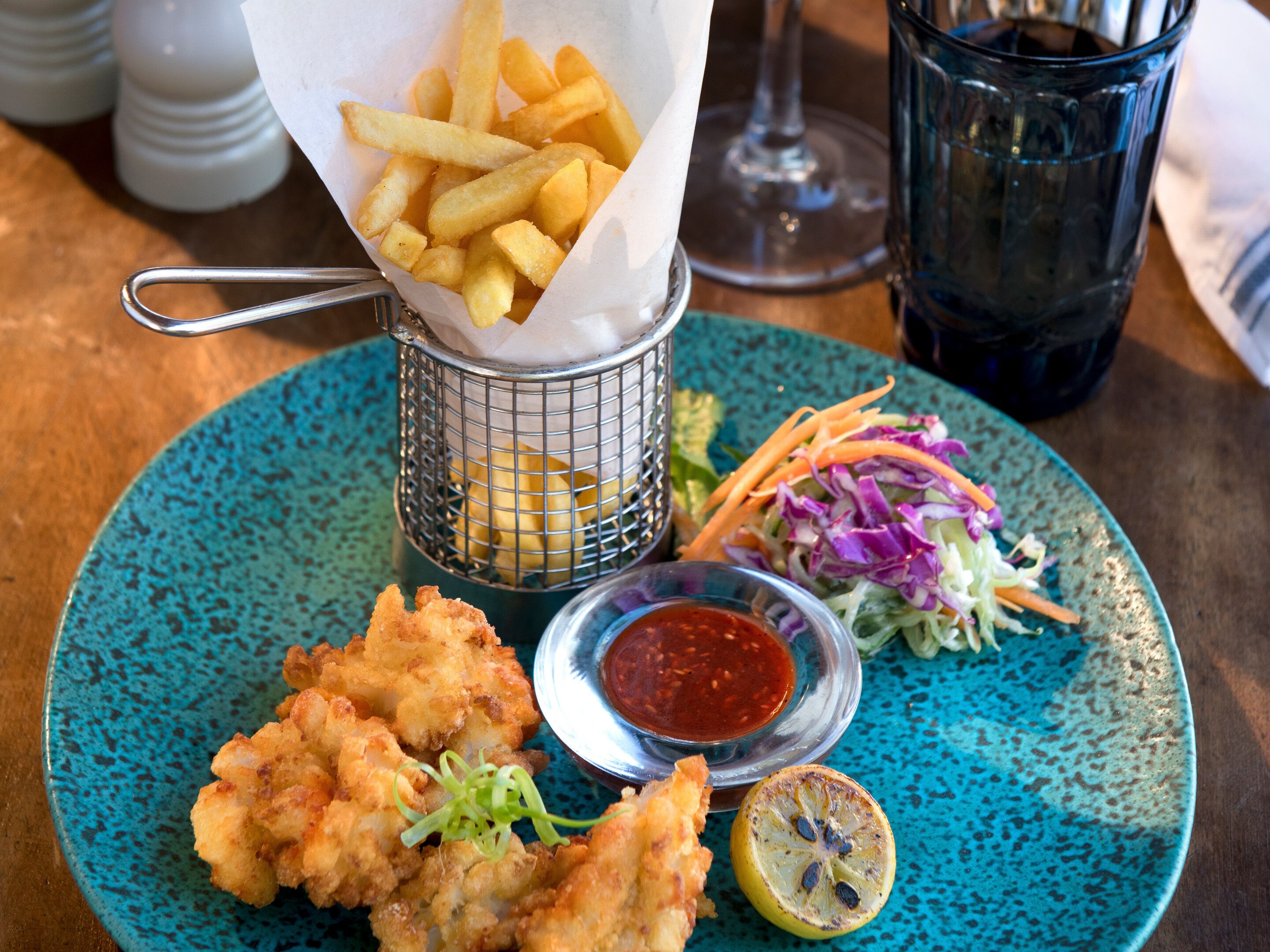A plate with fried food, a small bowl of sauce, and a lemon wedge.