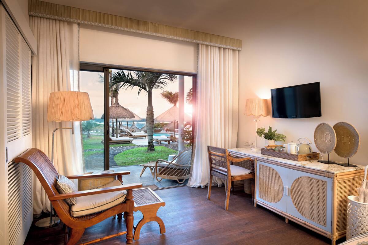 A room with a large window, a TV, a desk, and a seating area with chairs and a table.