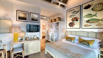 A bedroom with a bed, a desk, and a television. There are framed pictures on the wall and a ceiling fan.