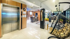 Un hall d’hôtel moderne comprenant un comptoir d’accueil, un fauteuil suspendu et un espace d’attente avec un comptoir et des sièges.