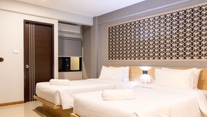 Une chambre d’hôtel avec deux lits, une tête de lit en bois, une lampe fixée au mur et une porte équipée d’un appareil de climatisation.