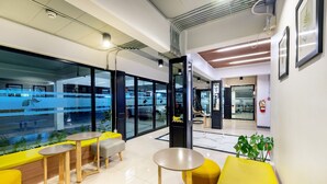 Un espace intérieur moderne avec des sièges jaunes, de grandes fenêtres et une vue sur l’extérieur.