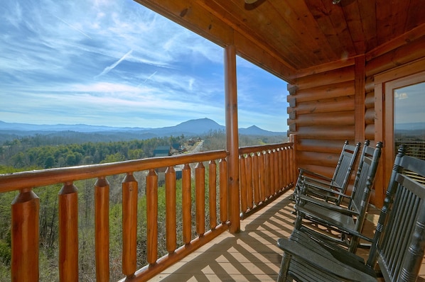 A wooden cabin with a balcony overlooking a mountainous landscape.