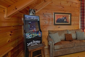 A retro arcade machine labeled "Jack Daniel's Old Time" in a wooden cabin setting.