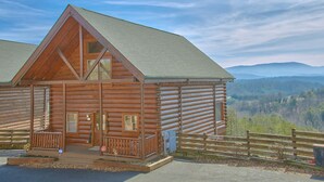 Een houten chalet met een veranda en uitzicht op de bergen.