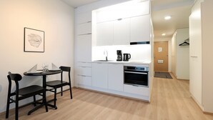 Une petite cuisine équipée avec un coin repas, une machine à café et un tableau encadré au mur.